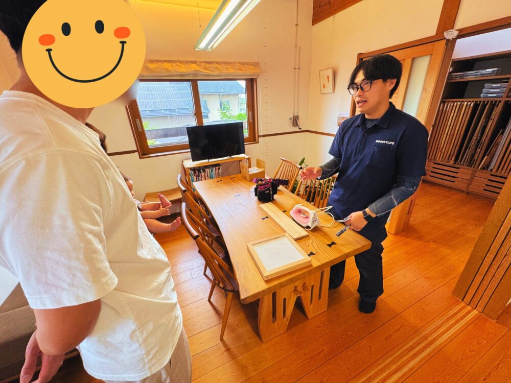 メンテナンスのプロが、ダイニングテーブルでオーナー家族に向けて道具の使い方を実演している様子