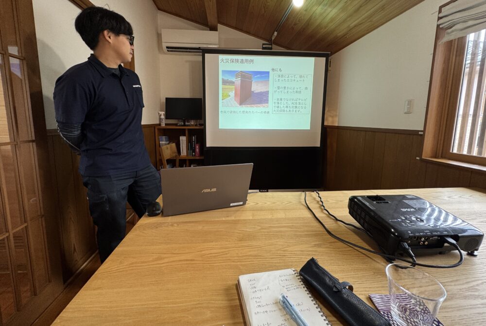 メンテナンスセミナーでスタッフがプロジェクターのスライドを使い「火災保険適用例」を説明している様子