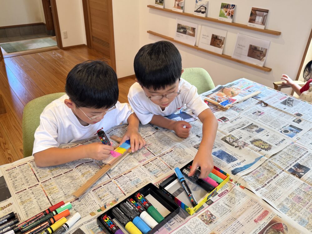 端材で作った木のゴム鉄砲にカラーマーカーで色を塗って仕上げる子どもたち