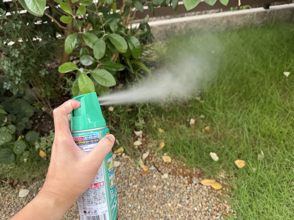 庭の植え込みと地面に向けてヤブ蚊バリアを噴射しているところ