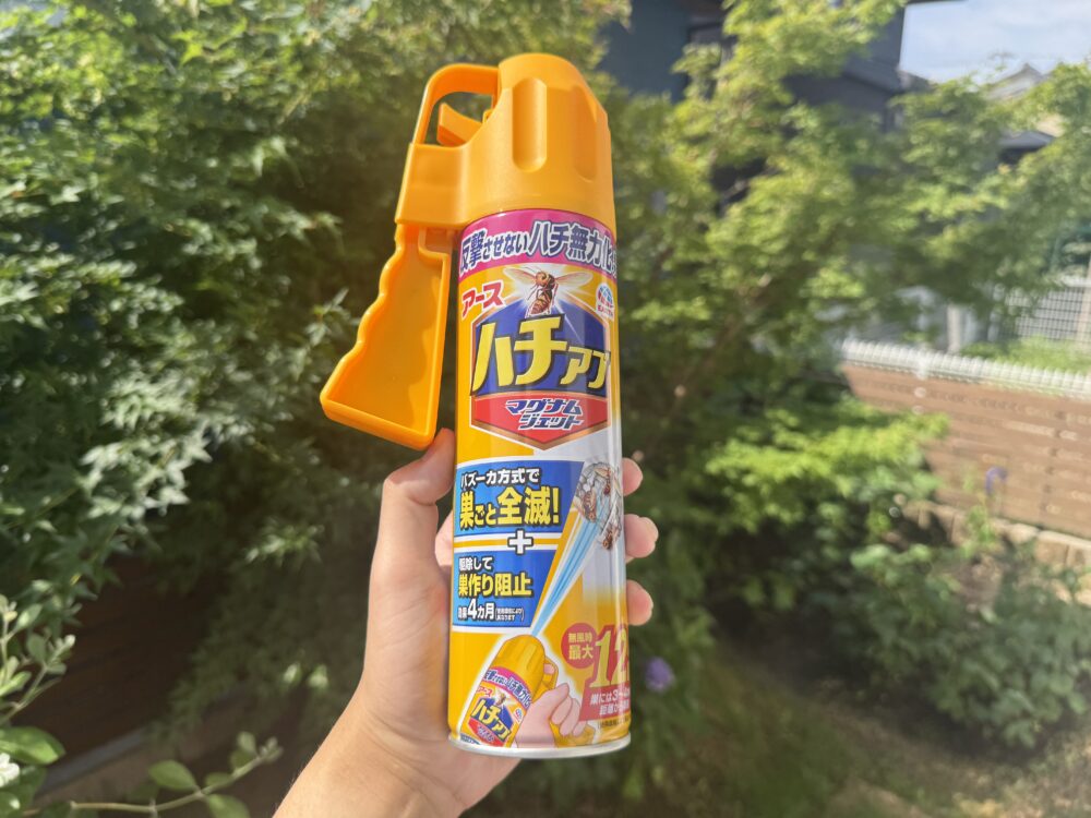 庭のもみじを背景に手に持ったアース製薬のハチアブマグナムジェット